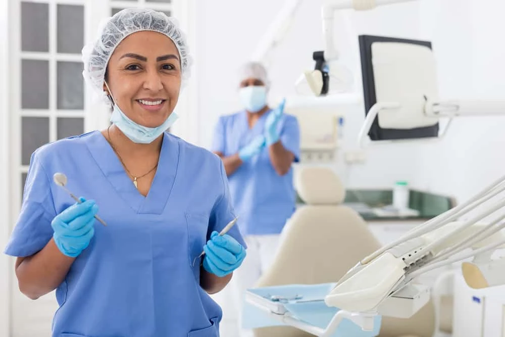A woman in a dental office holding a toothbrush.