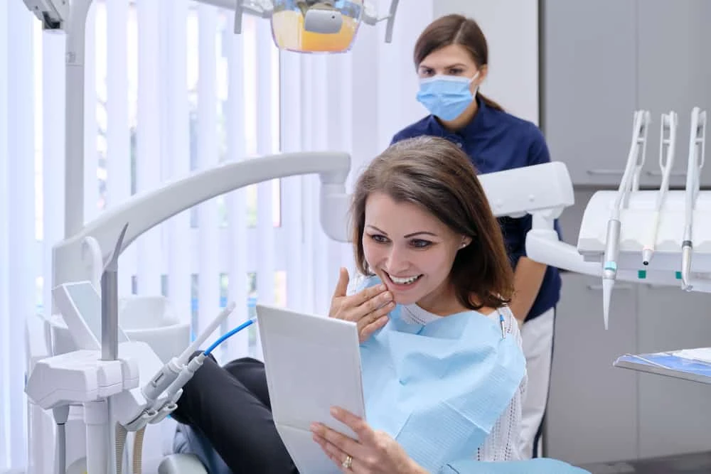 A woman in a dental chair is using a tablet.